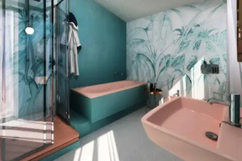 Bagno moderno con vasca rosa e doccia, carta da parati tropicale. Idee per come abbellire un bagno fai da te con stile e colore.