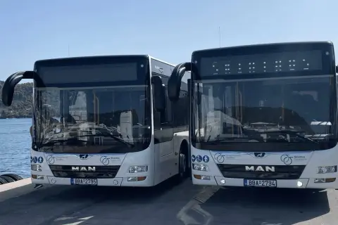 Två vita bussar står redo vid Skiathos flygplats för att transportera resenärer.