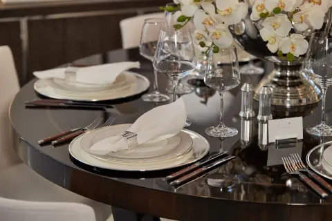 Elegant dukning med bestick, en vit servett med silverring och glas. En vacker blomsteruppsättning pryder bordet.