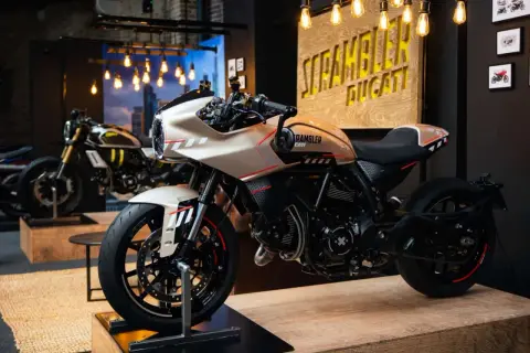 Una moto tipo scrambler color crema con detalles rojos y negros, lista para la aventura.
