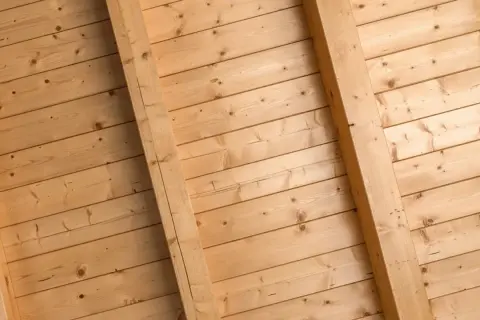 Holzdeckenpaneele mit sichtbaren Balken, bereit zum Streichen. Natürliche Holzmaserung.