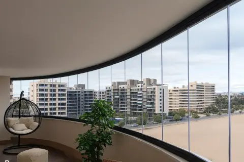 Modernas ideas para cerrar balcones: un espacio acogedor con silla colgante y vistas urbanas.