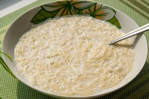 Pyszna zupa z makaronem w mleku, podana w miseczce z kwiatowym wzorem. Idealna na śniadanie lub lekki posiłek.