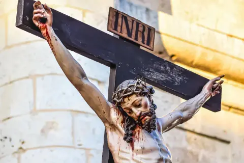 Figurka Jezusa na krzyżu, z koroną cierniową i krwawiącymi ranami. Scena przypomina śmierć kliniczną Jezusa, z tabliczką INRI.