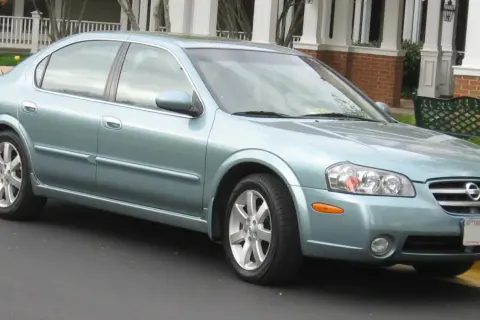 Jasnoniebieski Nissan Maxima 3.5 Turbo stoi przed domem z werandą.
