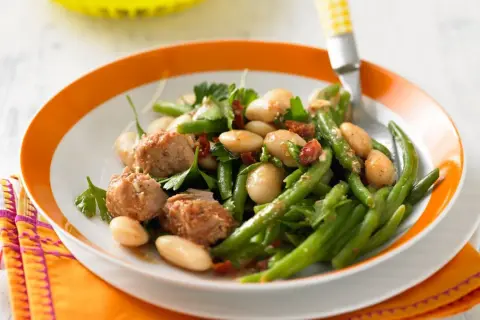 Bohnensalat rezept: Frischer Bohnensalat mit weißen Bohnen, grünen Bohnen, Thunfisch und Kräutern auf einem Teller mit orangem Rand.