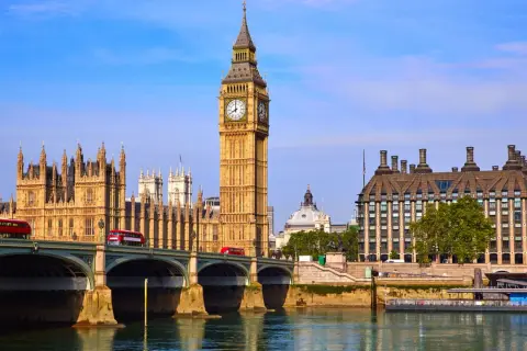 Big Ben Londyn z czerwonymi autobusami na moście i rzeką w tle.