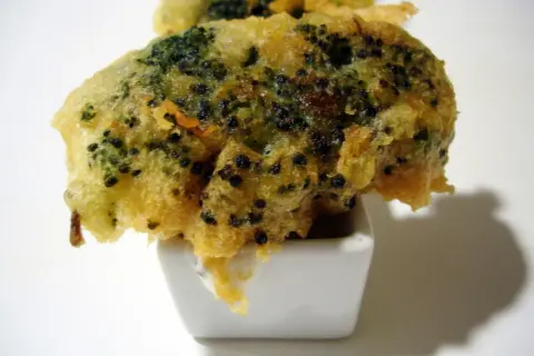 Brocoli en tempura crujiente, servido en un pequeño cuenco blanco con salsa.