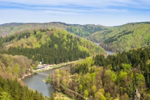 Góry Sowie w zieleni, z rzeką i mostem. Wyobraź sobie, jak dzieci biegają po ścieżkach wśród drzew.
