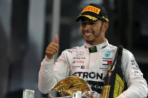 Lewis Hamilton, jeden z najlepsi kierowcy F1 wszechczasów, świętuje zwycięstwo z pucharem i szampanem.