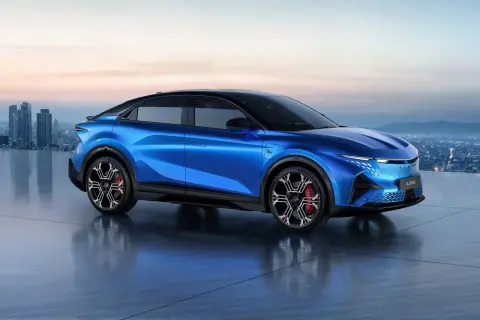 Alpine A390 blu elettrico, un'auto sportiva futuristica con un design aerodinamico, si staglia contro uno skyline cittadino al tramonto.