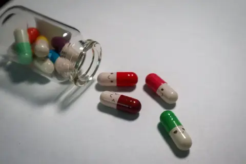 Kolorowe kapsułki, niektóre z uśmiechniętymi buźkami, symbolizują antydepresanty a psychotropy.
