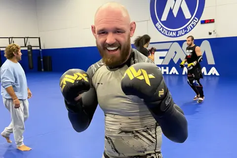 Viacheslav Borshchev ler glatt med boxningshandskar på en MMA-matta.