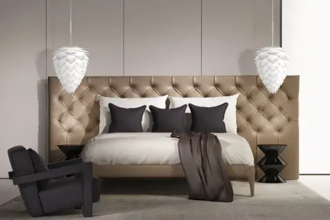 Elegancka lampa sufitowa do sypialni w kształcie szyszki, wisząca nad luksusowym łóżkiem z pikowanym zagłówkiem.
