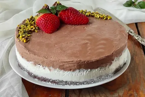 Deliziosa torta al gelato al cioccolato e panna, decorata con fragole, pistacchi e menta.