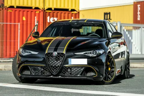 Czarna Alfa Romeo Quadrifoglio z żółtymi pasami i akcentami, gotowa do jazdy.