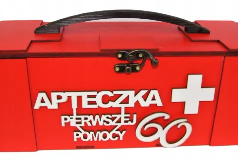 Czerwona, drewniana apteczka z napisem "Apteczka pierwszej pomocy" i białym krzyżem. Idealny prezent dla 60-latki.