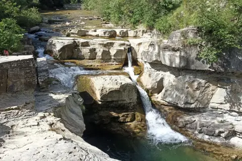 Cascate naturali scavate nella roccia vicino al monte Falterona. L'acqua cristallina scorre tra le rocce calcaree, creando un paesaggio suggestivo.