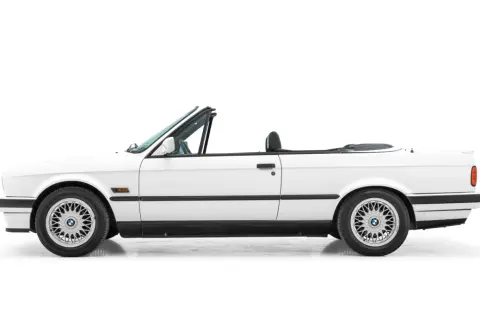 Vit cabriolet, en klassisk bmw 80 tal, med taket nere. Perfekt för sommarvägar.