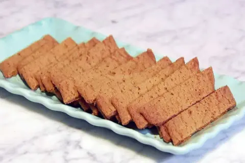En ljusblå bricka fylld med gyllene, tunna kola kakor. Perfekt för fikat!