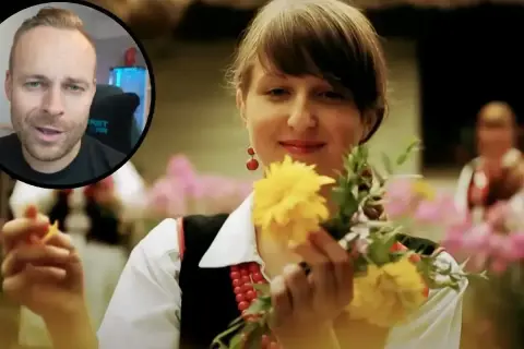 Mężczyzna w okrągłym kadrze mówi, podczas gdy młoda kobieta w tradycyjnym stroju, z koralami i kolczykami, trzyma bukiet żółtych kwiatów.