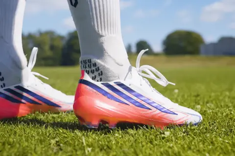 Scarpa calcio Adidas bianca con dettagli blu e rosa fluo. Pronta per scendere in campo e dominare la partita.