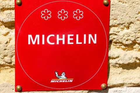 Targa rossa Michelin con tre fiori, simbolo di un ristorante 3 stelle Michelin.