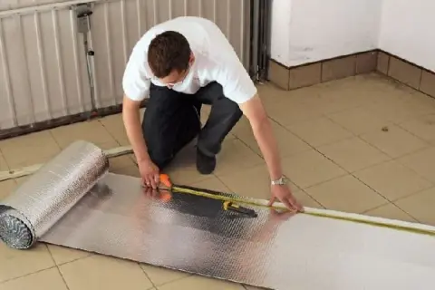 Mężczyzna mierzy materiał do ocieplenia bramy garażowej.