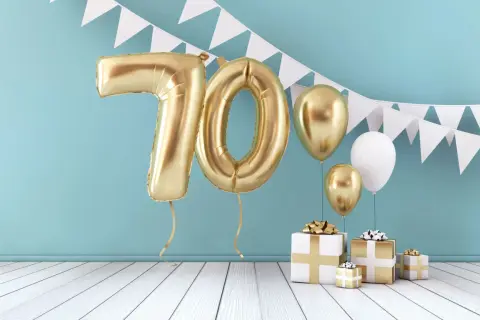 Złote balony z cyfrą 70 i prezenty tworzą piękną scenografię na życzenia na 70 urodziny.