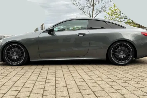 Szary Mercedes-AMG E53 coupe z przyciemnianymi szybami i czarnymi felgami stoi na kostce brukowej.