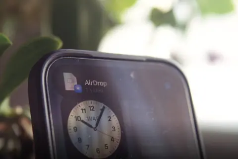Szybki udostępnianie wideo przez AirDrop. Na ekranie telefonu widoczny jest zegar.