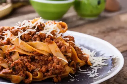 Pappardelle z bogatym sosem mięsnym, posypane parmezanem. Idealne pytanie: jakie mięso do spaghetti? Odpowiedź: mielone, duszone w sosie pomidorowym!