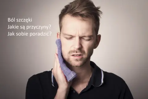 Mężczyzna z wyrazem bólu na twarzy przykłada fioletową ściereczkę do policzka, cierpiąc na ból szczęki.