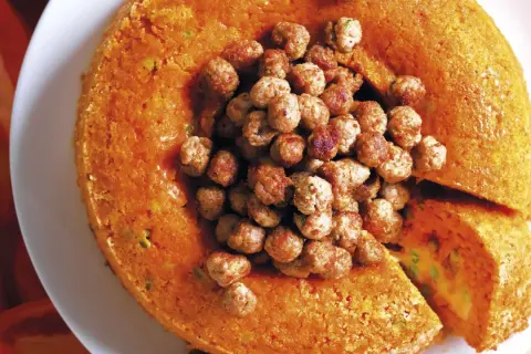 Sartù di riso al forno alla napoletana, un tortino dorato ripieno di piselli e formaggio, coronato da polpettine saporite.