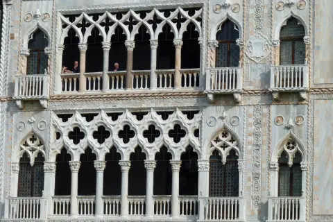 Dettaglio della Ca' d'Oro a Venezia, con le sue finestre traforate e balconi, dove si intravedono persone affacciate.