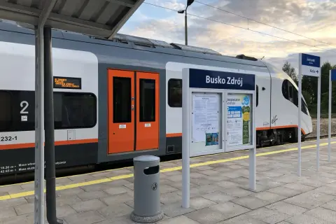 Pociąg do Buska Zdroju na peronie. Tablica informacyjna z nazwą stacji i rozkładem jazdy. Jak dojechać pociągiem do Buska Zdroju? Tu znajdziesz odpowiedź.