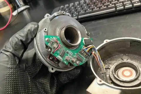 Napęd elektryczny zamiast szarpaka. Widoczny rozrusznik z płytką drukowaną i przewodami, trzymany w rękawiczce.