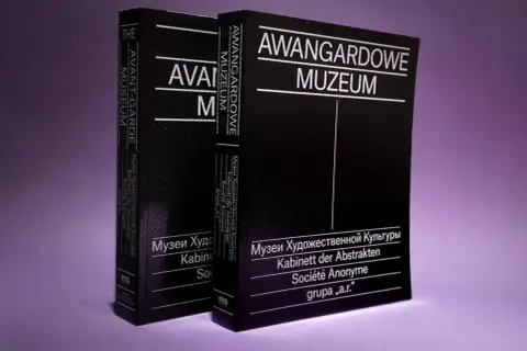 Dwie czarne książki z białymi napisami: "Avant-Garde Museum" i "Awangardowe Muzeum". W tle fioletowe.