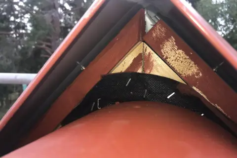 Detaljbild av taknock med vindskiveplåt och trädetaljer.
