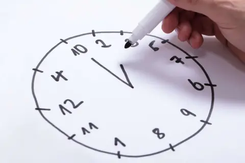 Hand zeichnet eine Uhr für einen Online-Demenztest. Die Zahlen sind unvollständig, was auf kognitive Herausforderungen hindeutet.