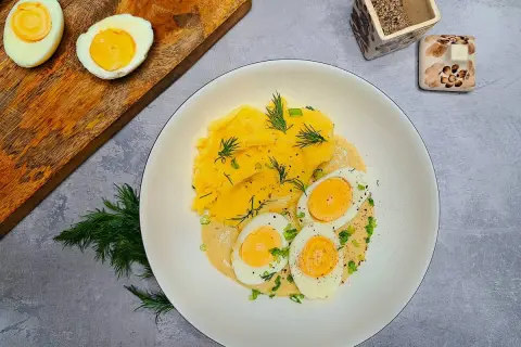 Jajka w sosie musztardowym z puree ziemniaczanym, udekorowane koperkiem i szczypiorkiem. Pyszne danie na obiad.