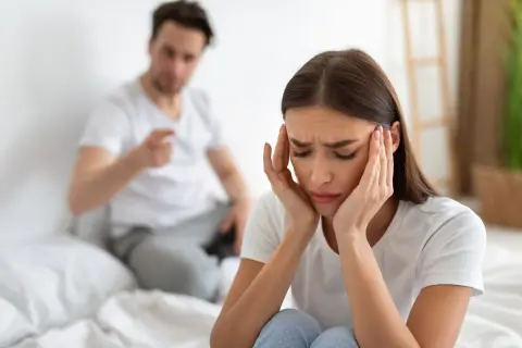 Mujer angustiada, con las manos en la cabeza, mientras su pareja le grita. Siente que mi mujer me maltrata psicológicamente.