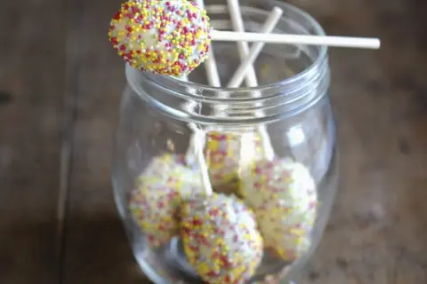 Bunte cake pops mit mascarpone, verziert mit Streuseln, stecken in einem Glas.