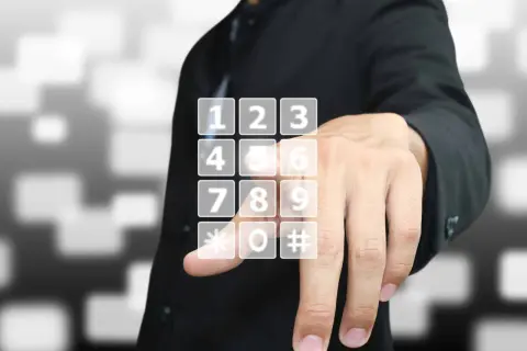 Dłoń wybiera wirtualny numer telefonu na ekranie.