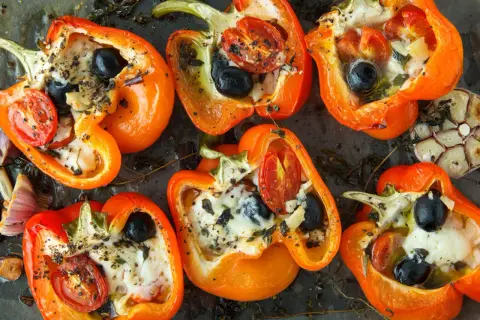 Poivrons orange farcis de fromage, olives et tomates, assaisonnés d'herbes. Un délice de poivrons marinés prêt à être dégusté.