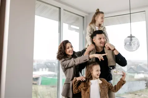 Famiglia felice in una casa luminosa, con la madre che indica il futuro. Nonostante si possa vendere casa senza lasciare a mio figlio nulla, l'amore è il vero patrimonio.
