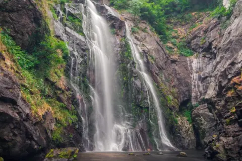 La Fervenza das Hortas, una cascada imponente que desciende por rocas cubiertas de vegetación, creando un espectáculo natural.