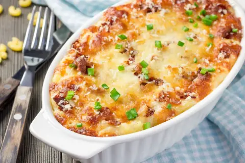 Zapiekane mac and cheese z chrupiącym serem i zieloną cebulką, gotowe do podania.