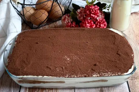 Tiramisù pronto per essere gustato! La ricetta tiramisù con 500 g mascarpone è un classico. Uova, fiori e latte completano la scena.