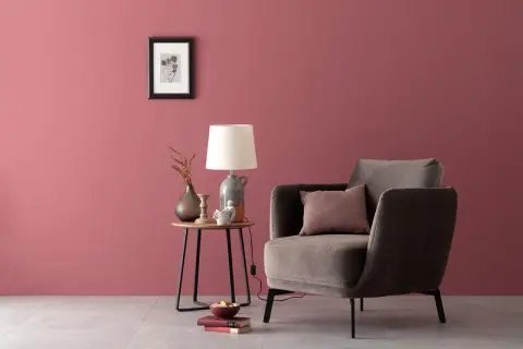 Gemütliche Ecke mit einem Sessel und Beistelltisch. Die Wand in einem warmen, englischen Rosenrot kombiniert mit dunklen Möbeln und Deko.